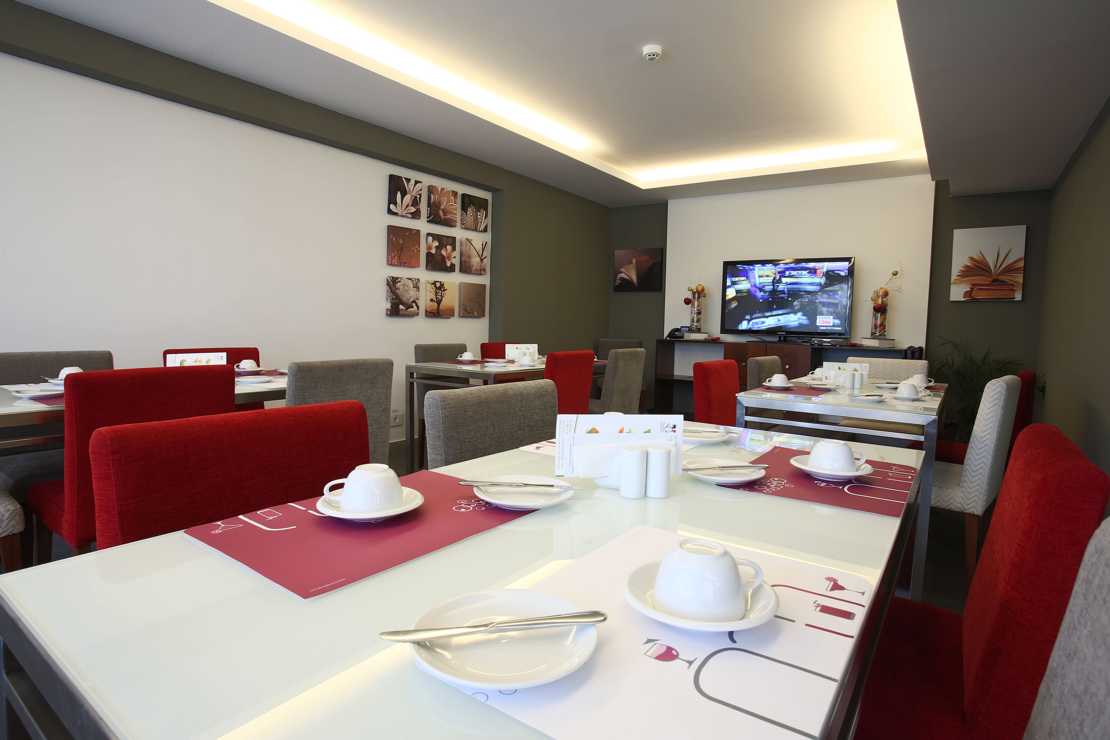 A dining area with tables set for breakfast, including plates, cups, and cutlery.