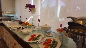 A buffet setup with various food items, including fruits, vegetables, and covered dishes. - Monoberge Byblos Hotel (Byblos)