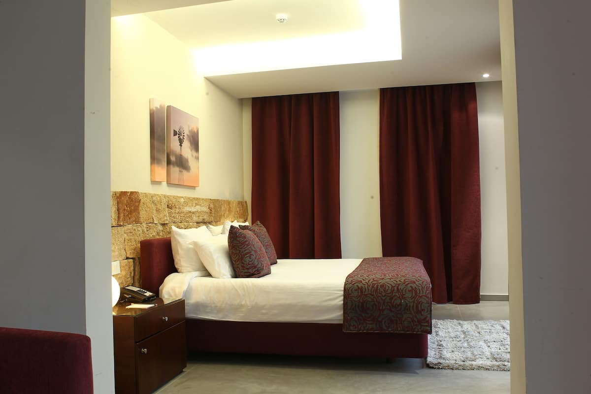 A modern bedroom with a bed, nightstand, and artwork on the wall.