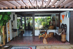 A traditional wooden structure with a tiled floor, a wooden bench, and a large woven vase. - Arambaré Buzios Hotel (Búzios)