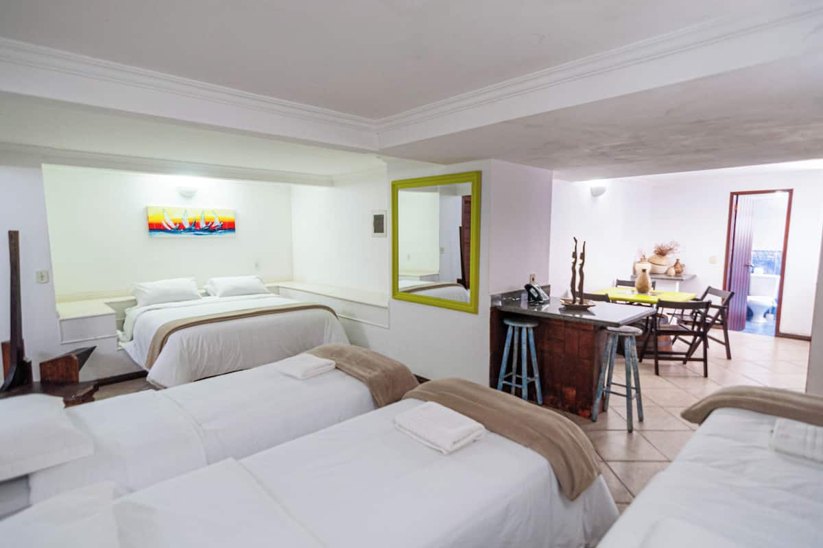 A hotel room with two beds, a desk, a chair, and a bathroom visible through an open door.