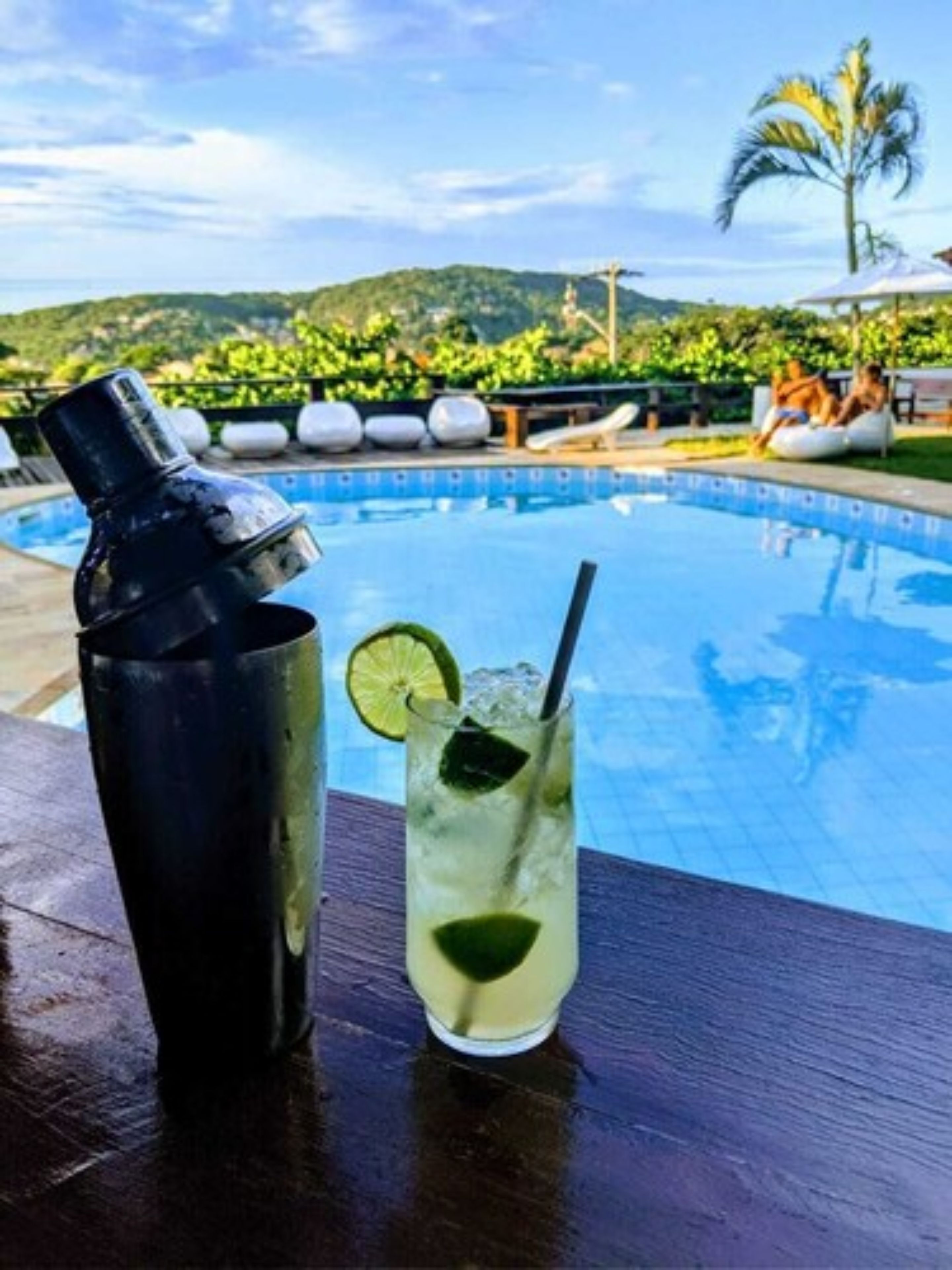 Ambiente junto à piscina com bebida e coqueteleira.