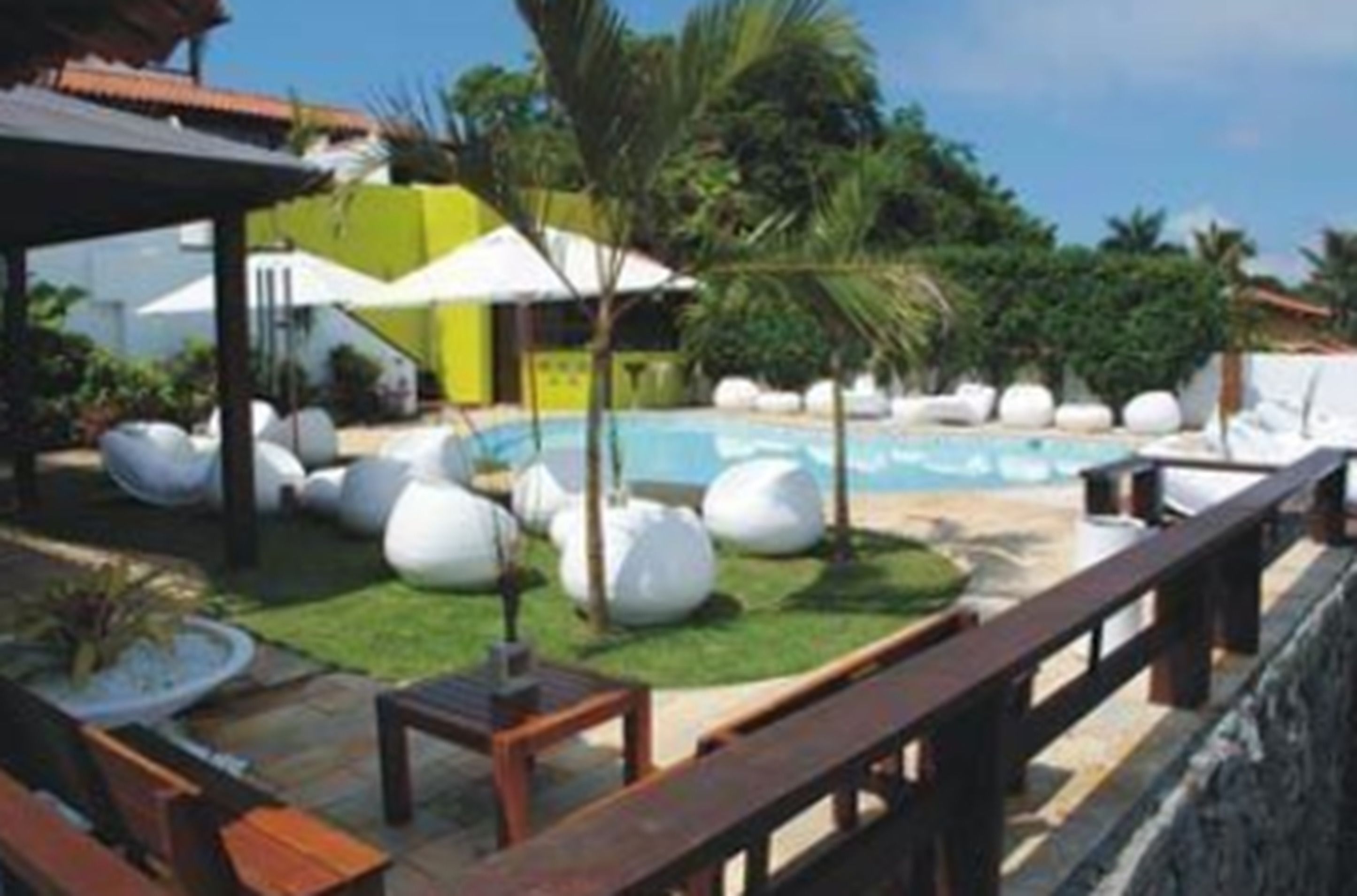 A pool area with lounge chairs, a wooden deck, and a stone wall.