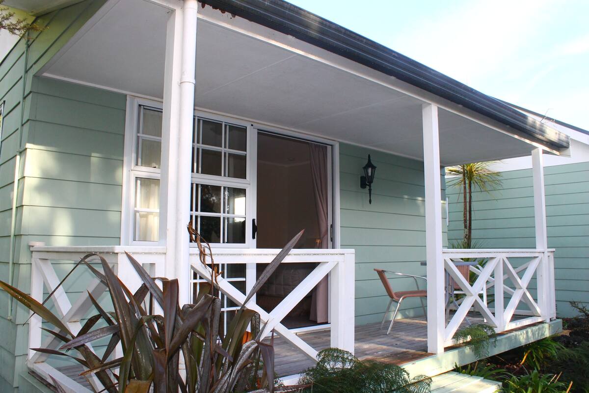 A light green building with a white porch and a sliding glass door.