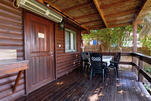 En træhytte med en overdækket veranda, et bord og stole.