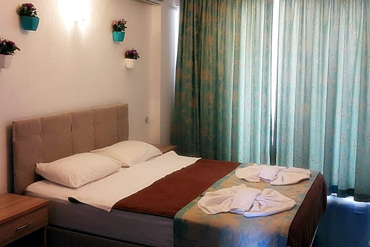 Una habitación de hotel con una cama, una mesita de noche y dos macetas en la pared.