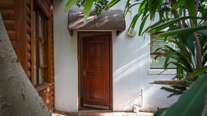 A wooden door with a small porch area, a window, and a potted plant.