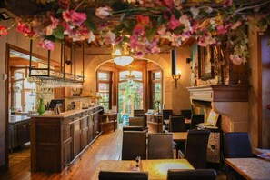 Een restaurantinterieur met een bar, eettafels en uitzicht door de ramen.