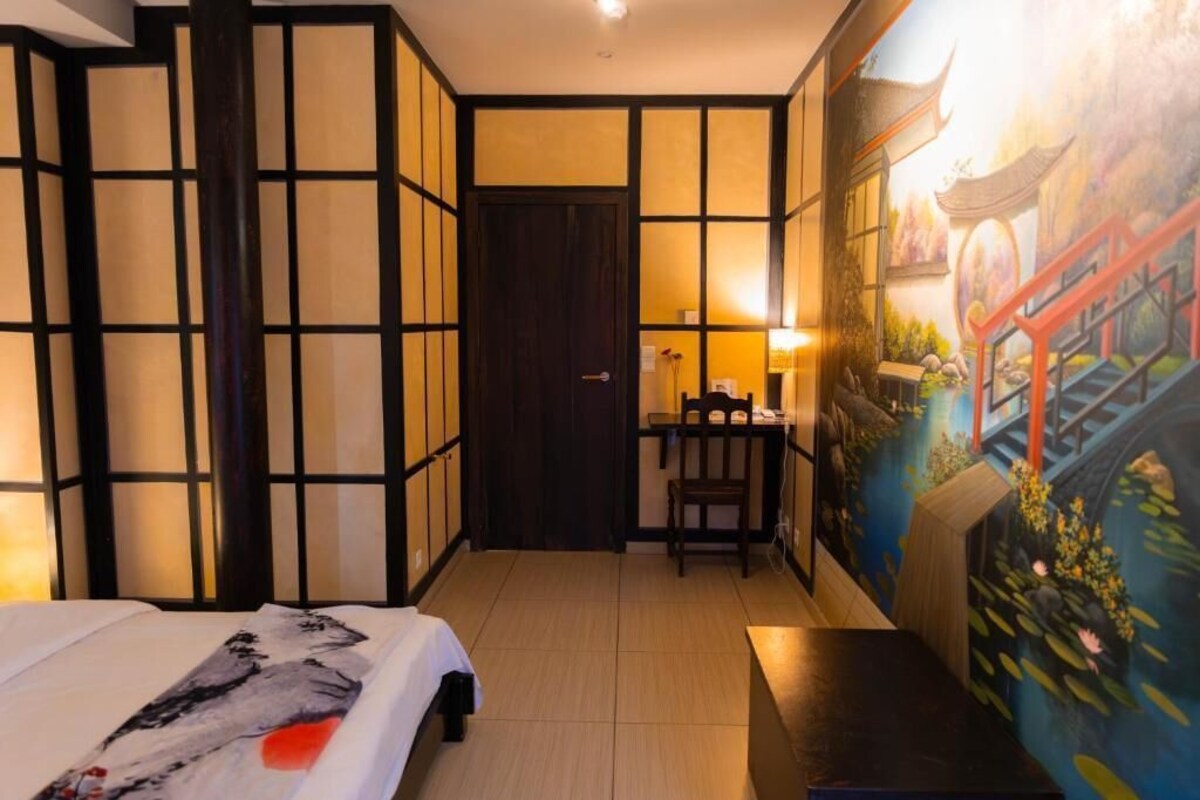 Een hotelkamer met een bed, een bureau en een muurschildering.