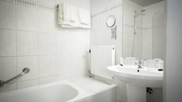 Een badkamer met een bad, een wastafel, een spiegel en een handdoekhouder.