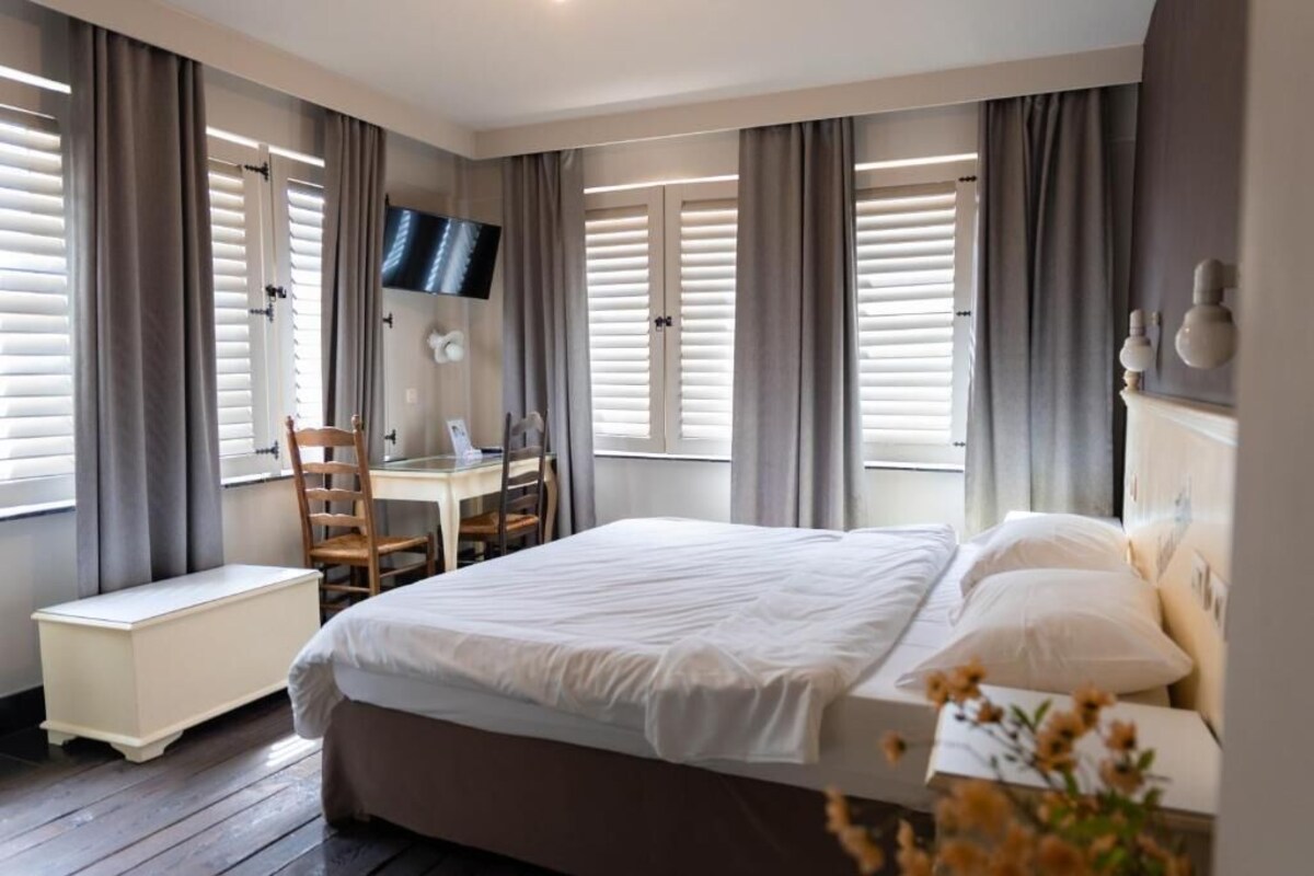 Een slaapkamer met een bed, een bureau en een stoel.