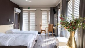 Una habitación de hotel con dos camas, un escritorio, una silla y un florero.