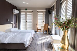 Een hotelkamer met twee bedden, een bureau, een stoel en een bloemenvaas.