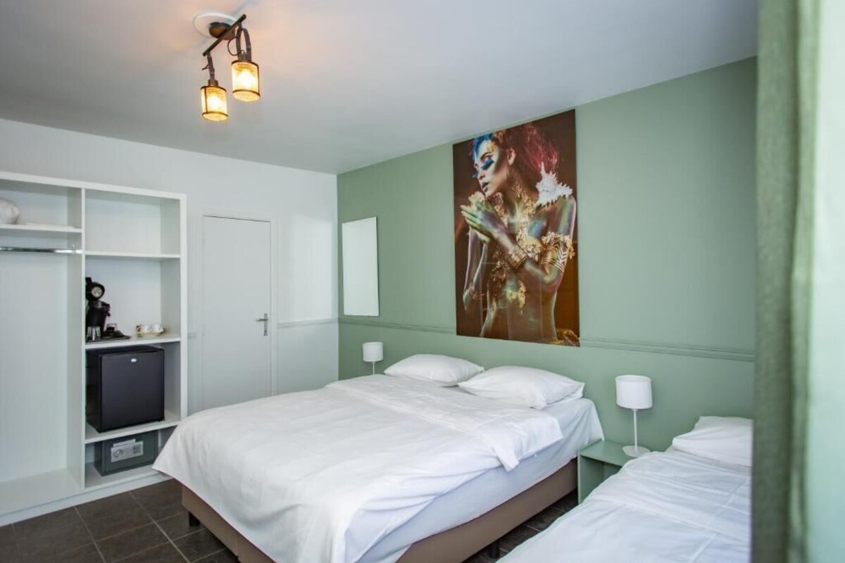 Een hotelkamer met een bed, een kledingkast, een bureau en een kunstwerk aan de muur.