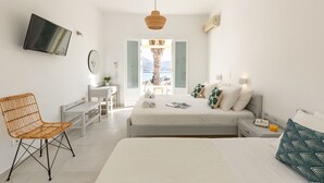 Une chambre d’hôtel moderne, équipée d’un lit, de tables de chevet, d’une chaise, d’un téléviseur et offrant une vue sur l’extérieur.