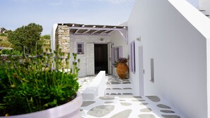 Un étroit sentier pavé de pierres mène à un bâtiment blanc dont la façade est également en pierre.