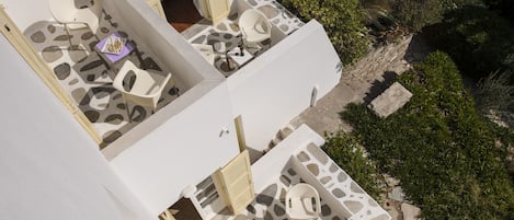 A two-story building with a patio area featuring white furniture and a stone pattern floor.