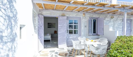 A white building with a stone floor, white furniture, and a balcony.