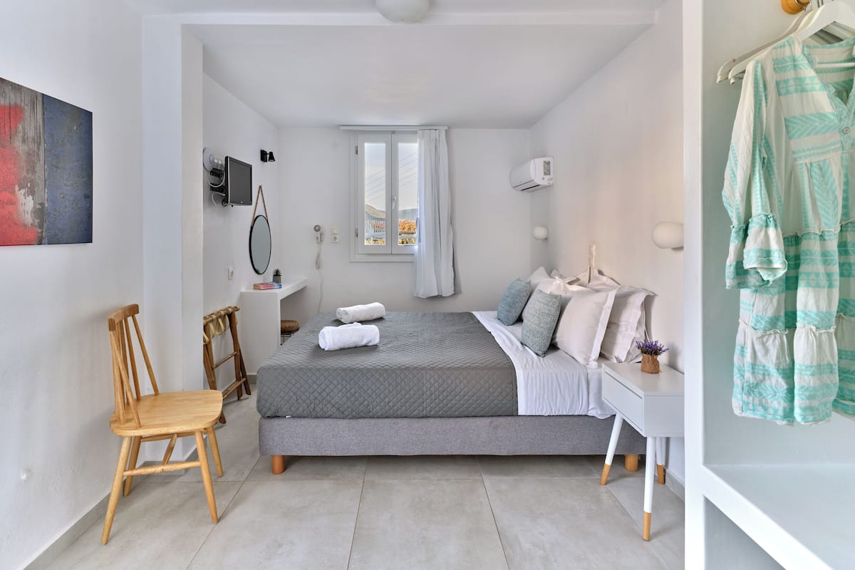 A modern bedroom with a bed, a chair, a desk, and a wardrobe.