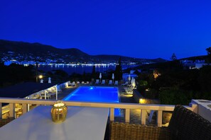 An infinity pool with a view of a cityscape at night. - Akrotiri Hotel (Paros)