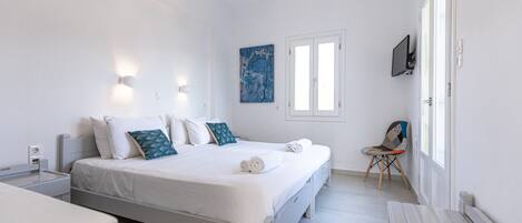 A modern bedroom with a bed, bedside tables, a chair, a TV, and a window.