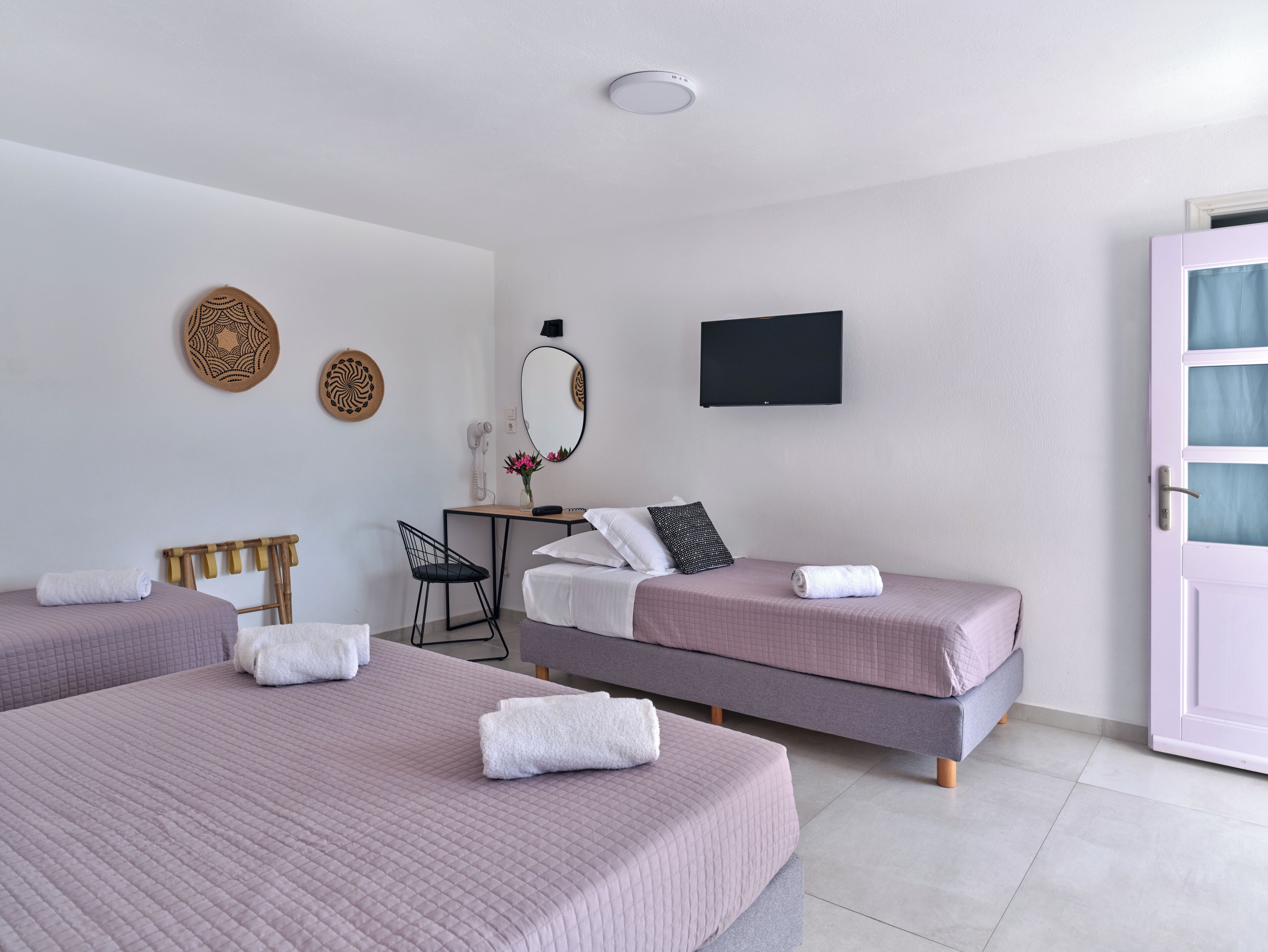 A hotel room with two beds, a desk, a chair, a mirror, and a TV.