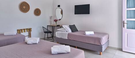 Ein Hotelzimmer mit zwei Betten, einem Schreibtisch, einem Sessel, einem Spiegel und einem Fernseher.
