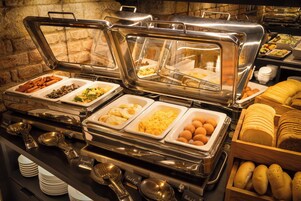 Un buffet con diversi cibi, tra cui uova, carni e pane.