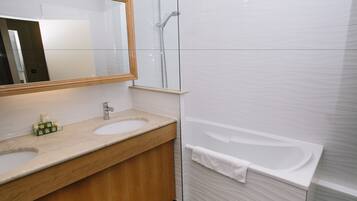 Un baño con dos lavamanos, un espejo y una bañera.