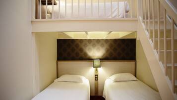 Een hotelkamer met twee eenpersoonsbedden, een nachtkastje met een lamp en een trap.