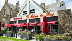 Un restaurant appelé « Le Relais du Roy », doté d’une terrasse et de parasols rouges.
