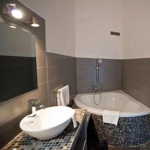 Un baño moderno con una bañera independiente, un lavamanos y un espejo.