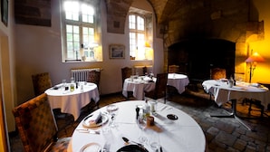 A dining area with round tables, chairs, and a stone fireplace.