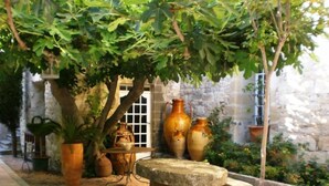 A courtyard with a stone table, potted plants, and terracotta pots.