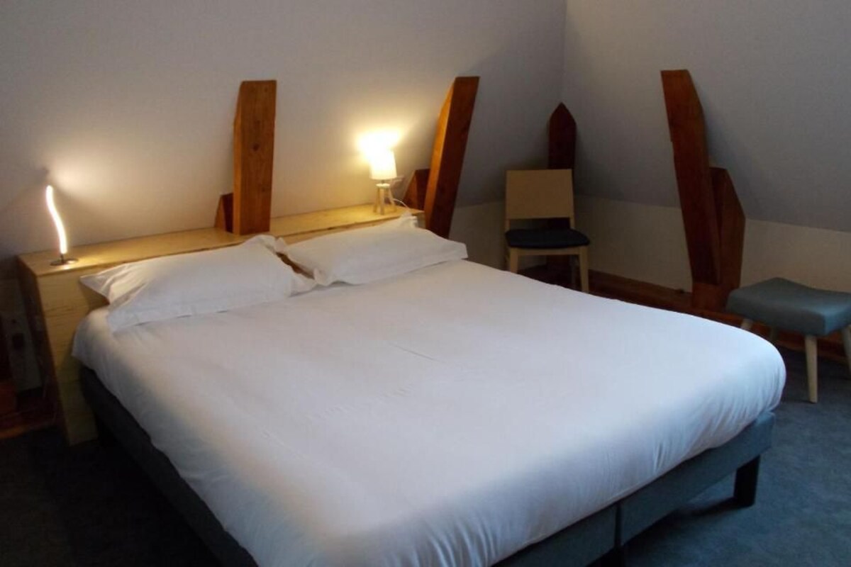 Een hotelkamer met een groot bed, bedlampen, een stoel en een tafeltje.