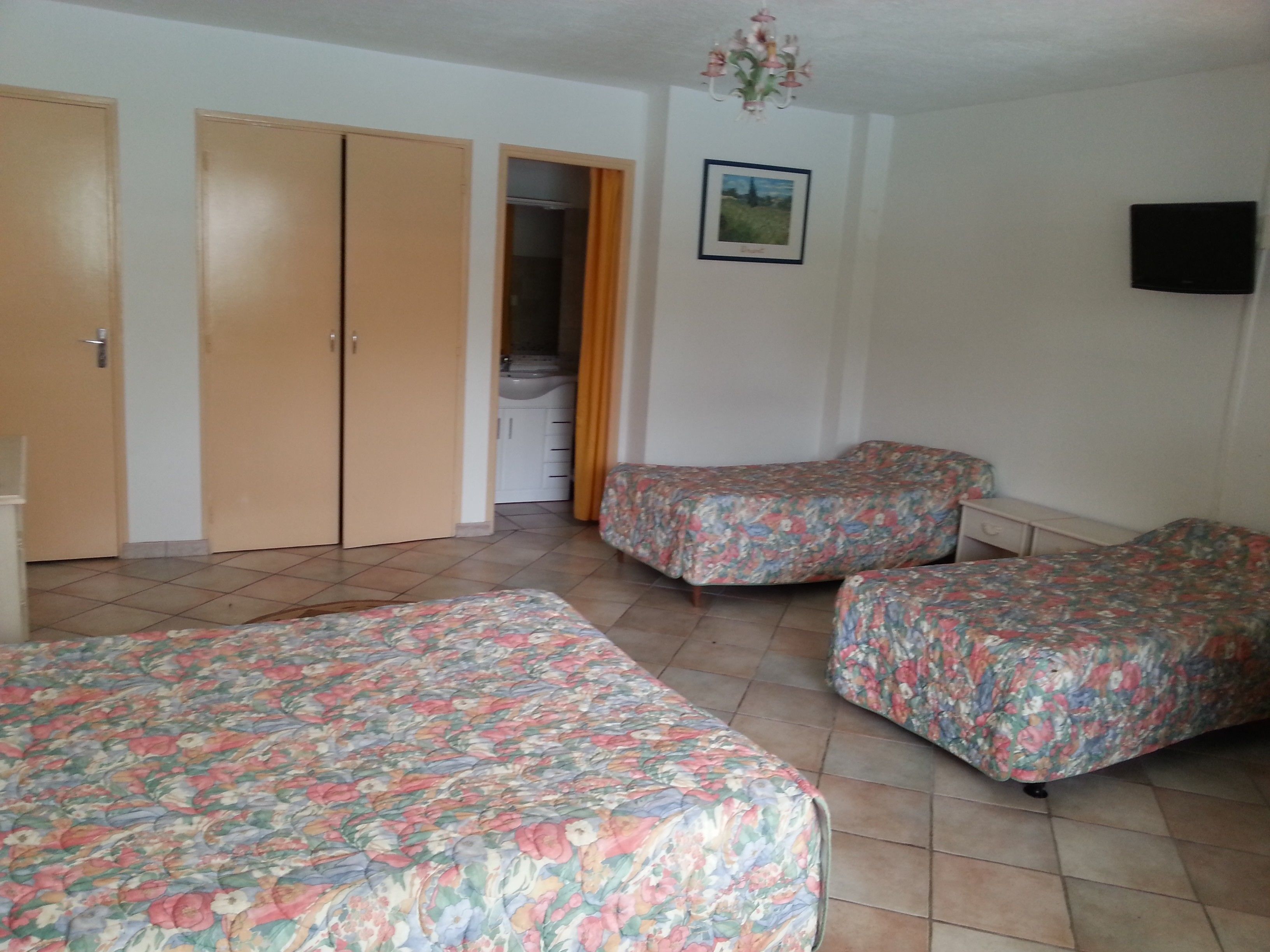 A room with two single beds, a wardrobe, a bathroom, and a TV on the wall.