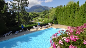 Una piscina al aire libre, sillones reclinables de piscina