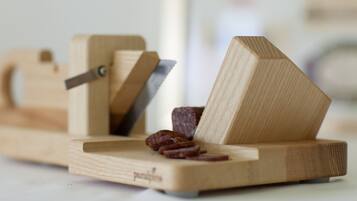 A wooden meat slicer with a handle and a blade, placed on a flat surface.