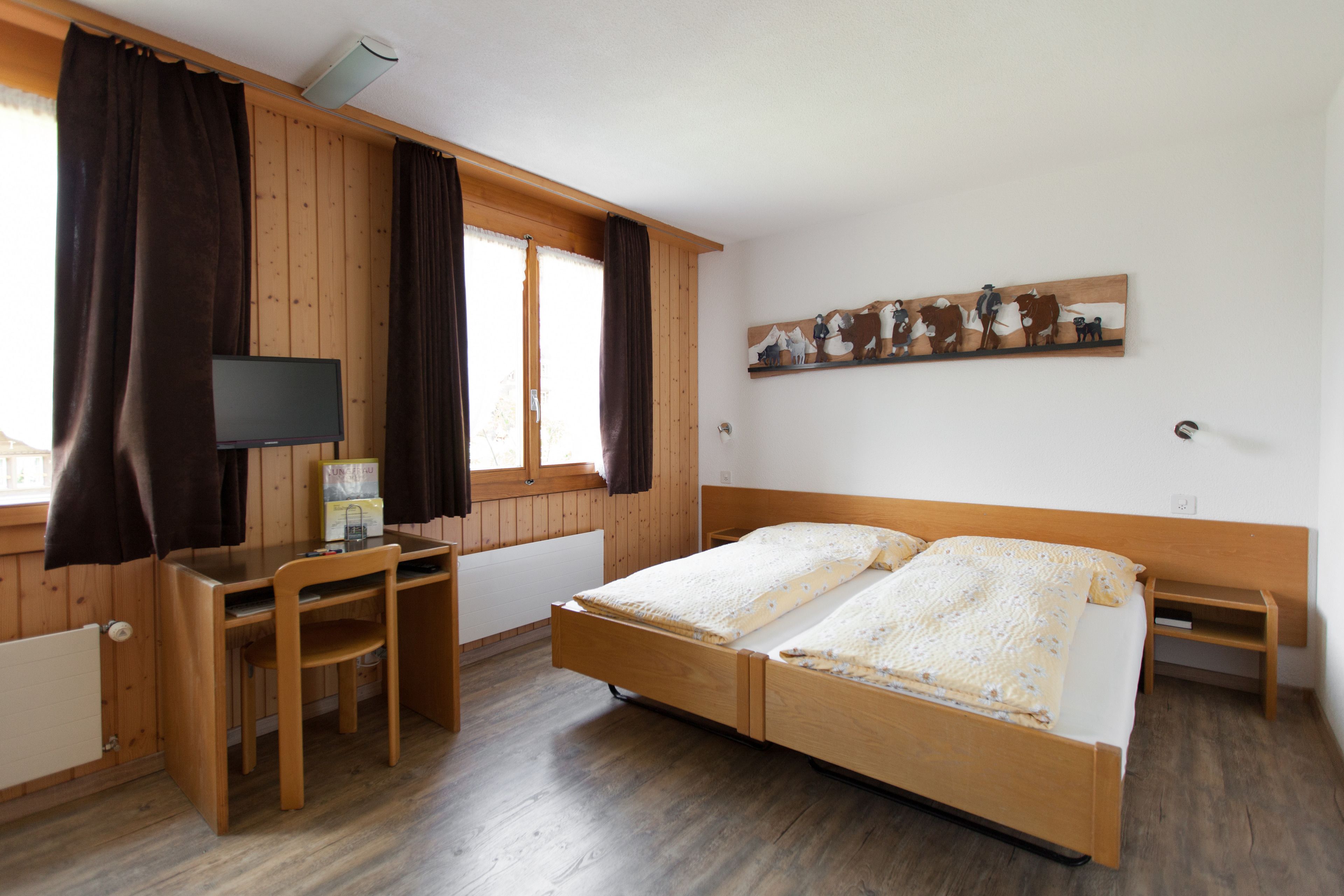 Habitació amb un llit de fusta, un escriptori i una cadira.
