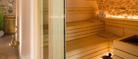 Una sauna con bancos de madera, un banco de madera con una toalla y un cubo de madera.