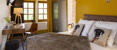 Habitación de hotel con cama, escritorio con silla, armario y un adorno de cabeza de venado en la pared.