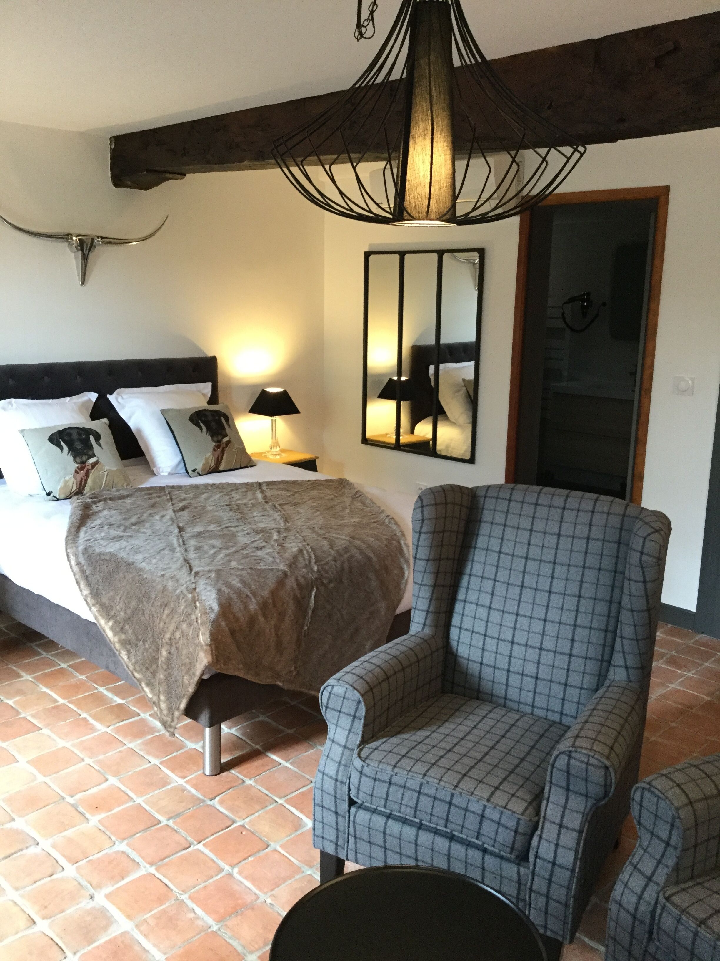 Une chambre à coucher avec un lit, une chaise, un miroir et un luminaire suspendu.