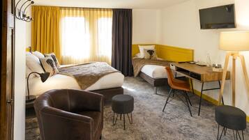 A hotel room with a bed, a desk, a chair, a TV, and a lamp.