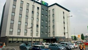 Un hôtel à plusieurs étages avec un parking situé devant.
