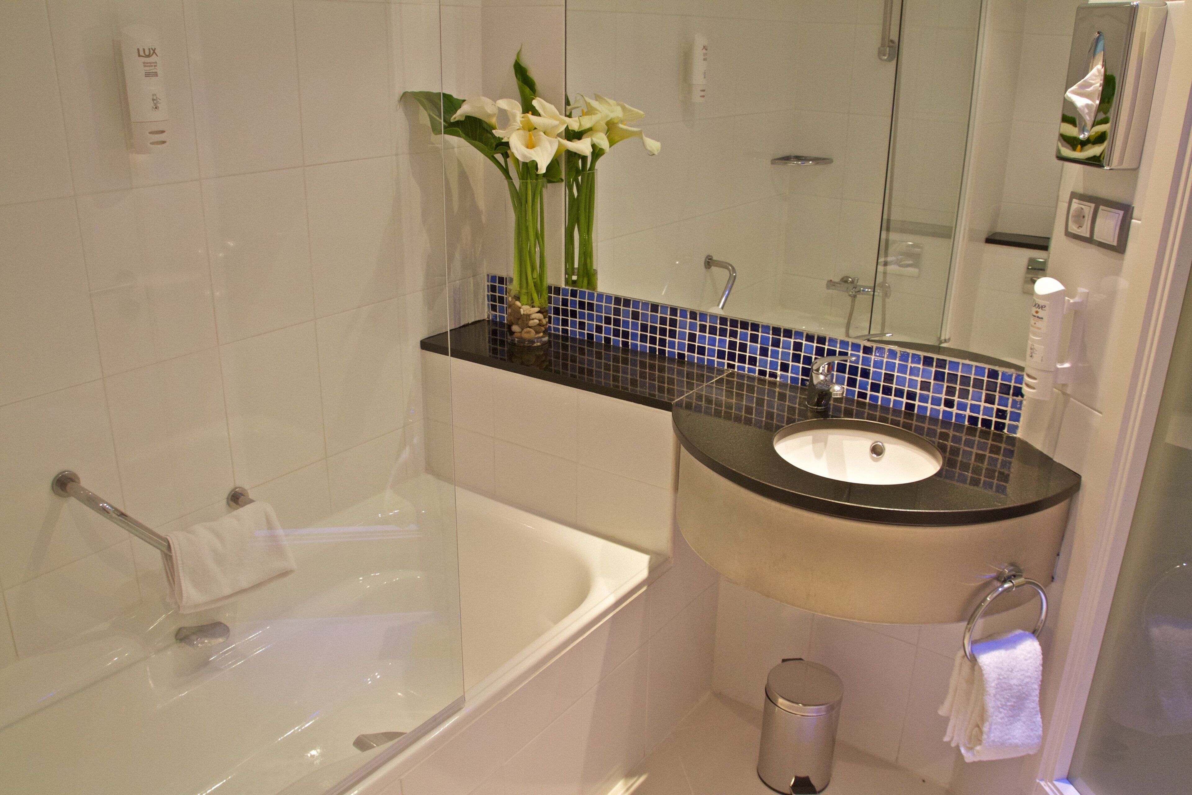A bathroom with a bathtub, sink, and mirror.