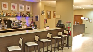 Eine Bar mit Theke, Barhocker, einer Kaffeemaschine und einer Auswahl an Flaschen.