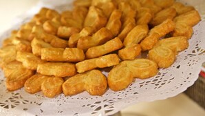 Eine Schale goldbraun frittierter Snacks auf einer weißen Spitzentischdecke.