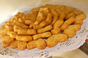 Eine Schale goldbraun frittierter Snacks auf einer weißen Spitzentischdecke.