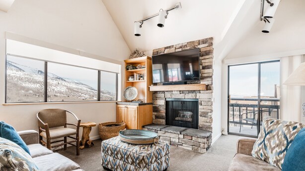 A spacious living room with a fireplace, large windows, and a cozy seating area. - The Loft at Mountain Village by All Seasons Resort Lodging (Park City)