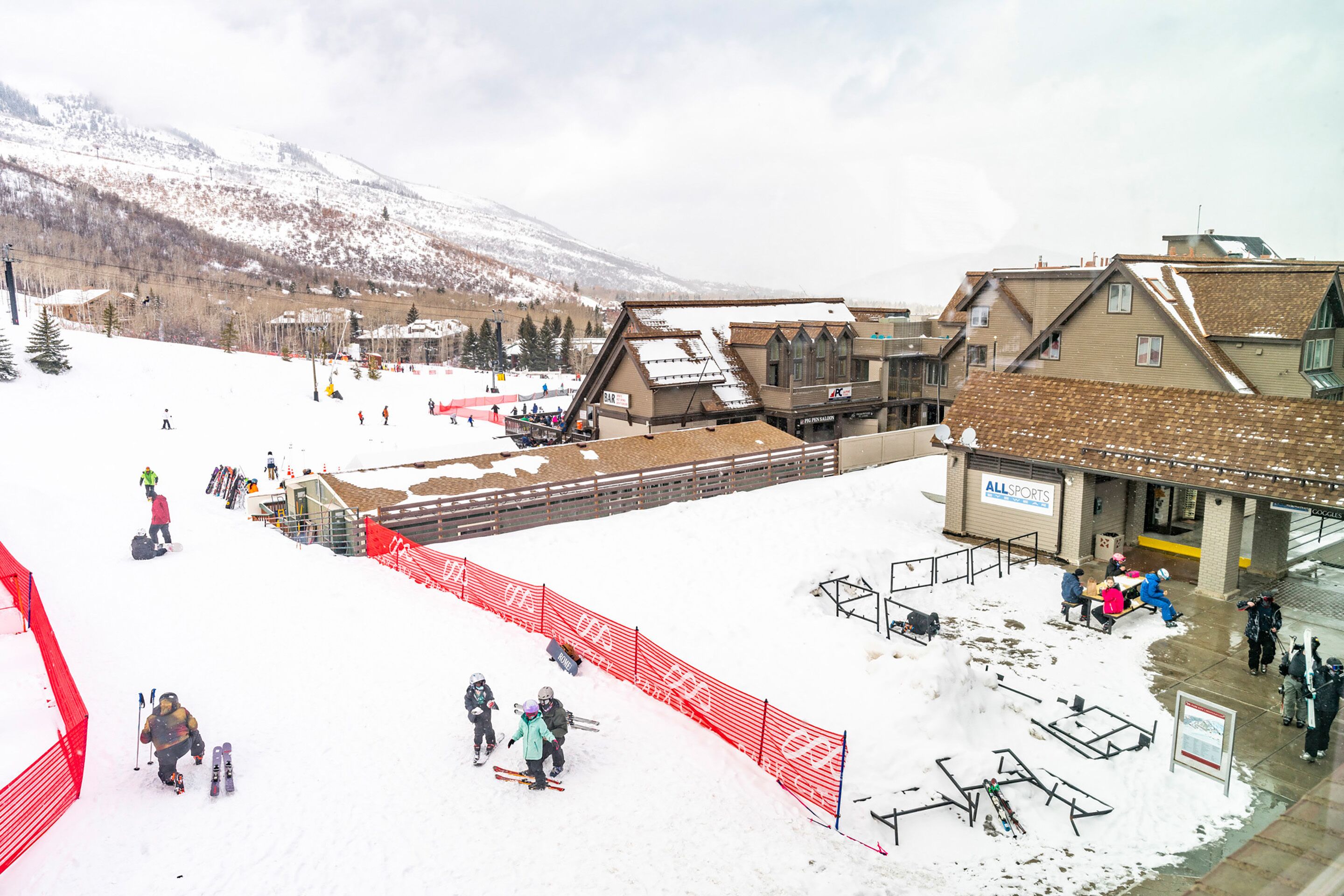 A ski resort with a building labeled "ALL SPORTS" and a ski lift in operation.